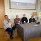 Lived-experience panel discussion at the conference, participants are sat around the table having a discussion at the front of the conference hall.