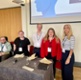 Cardiff and Vale UHB Youth Board panel discussion at the conference. Participants are stood and sat around a table at the front of the conference hall, looking at the camera and smiling.
