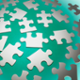 Silver puzzle pieces on a green background