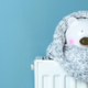 Polar Bear on a radiator with a scarf on with a blue background