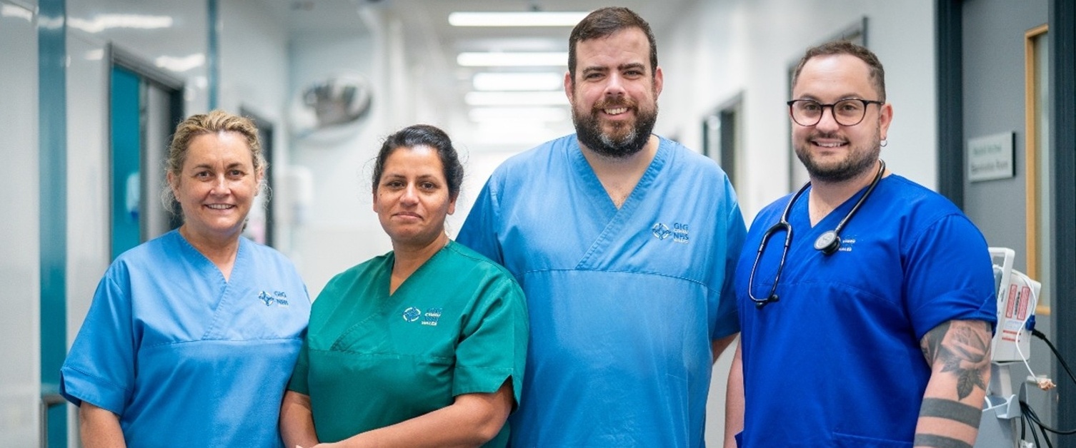Four clinicians are stood side-by-side in a hospital corridor.