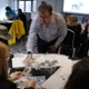 A group of people are sat at a table and talking as they look at papers during a workshop.