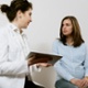 A healthcare professional is holding a booklet open and talking to a patient.