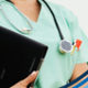 A healthcare professional is holding a laptop.